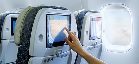 Woman reaching out to a touchscreen in aircraft interior