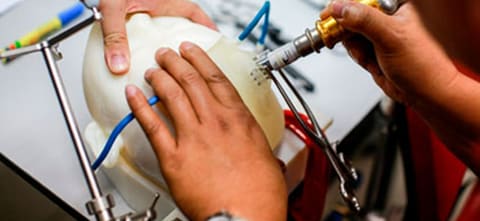 doctors performing a practice surgery on a manekin head made for CBMTI using PolyJet materials and a Stratasys Printer