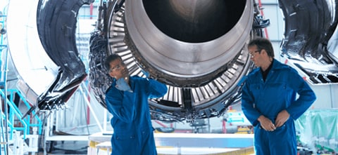 2 men working in the Aerospace industry, standing under a plane and making repairs together