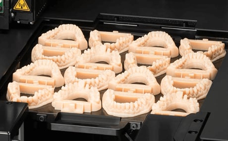 A close up of a 3D printer, where dental molds have just been printed