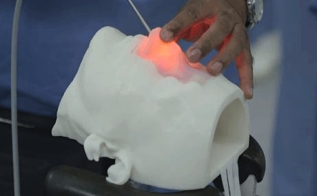 a doctor performing a practice surgery on a manekin head made for CBMTI using PolyJet materials and a Stratasys Printer